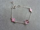 Bedelarmband met vlindertjes en roze en witte bloemen.